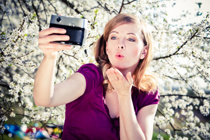 Nadine Petry macht ein Selfie mit einem blühenden Kirschbaum im Hintergrund