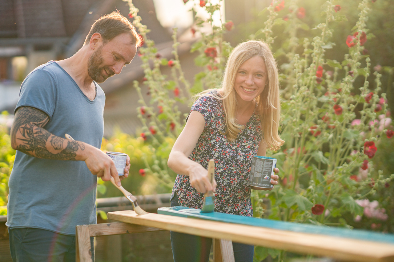 Nadine Petry und Joel Rakete streichen Bretter einer Gartenbank.